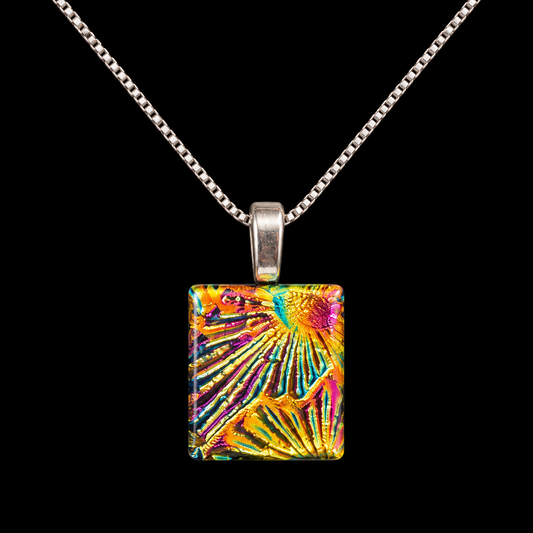 A silver chain necklace with a square pendant featuring a vibrant, multicolored abstract pattern of radiating lines in yellow, orange, pink, and blue, set against a solid black background.