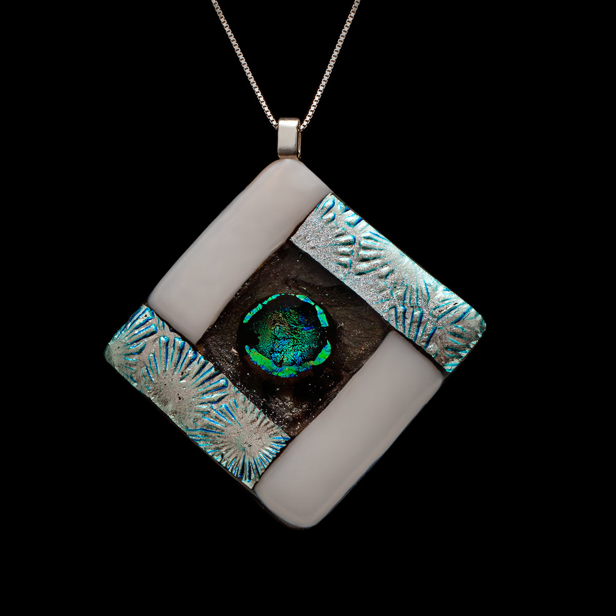 Close-up of a handmade white and silver fused glass necklace with a circular green-blue dichroic glass centre.