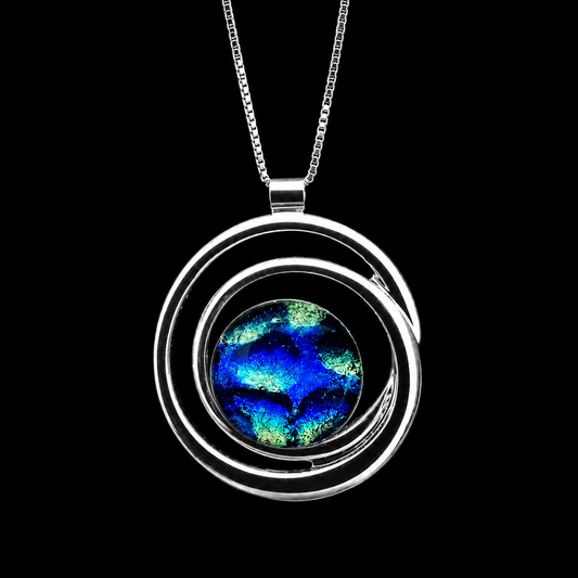A silver necklace with a circular, spiral-like pendant featuring a vibrant blue and green iridescent stone in the center, set against a solid black background.