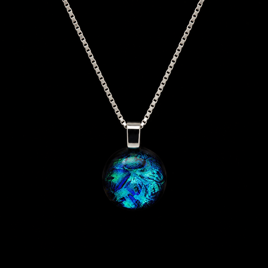A silver box chain necklace with a round glass pendant featuring a vibrant blue and green iridescent pattern, set against a solid black background.