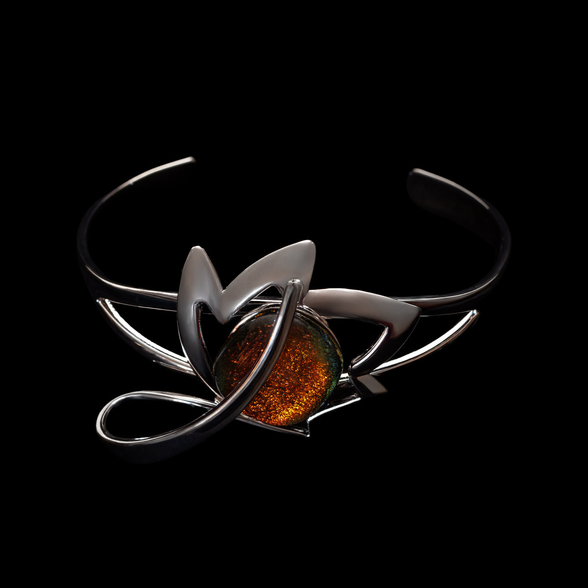 Silver bracelet with a central orange dichroic glass stone on a black background