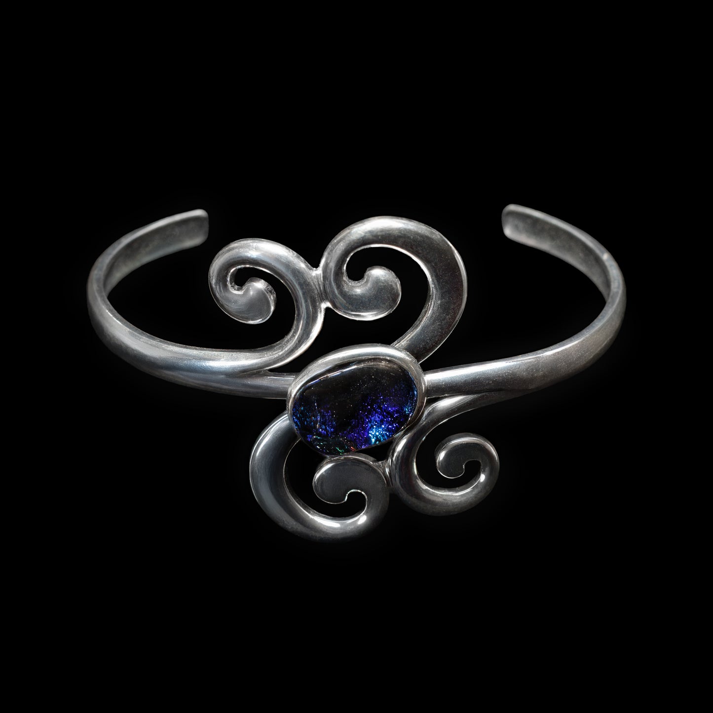 Silver scroll bracelet with a blue gemstone on a black background
