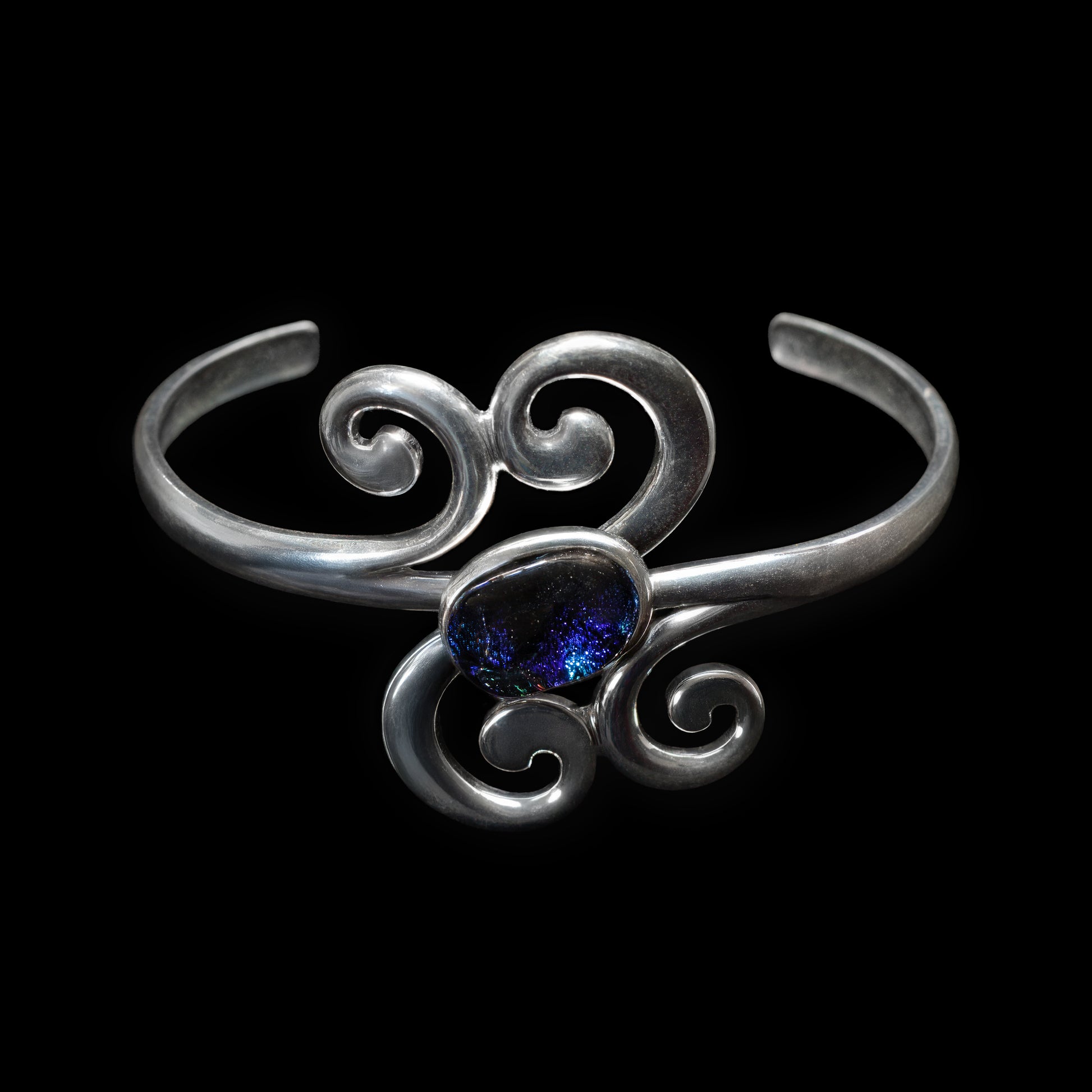 Silver scroll bracelet with a blue gemstone on a black background