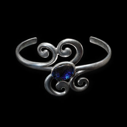 Silver scroll bracelet with a blue gemstone on a black background