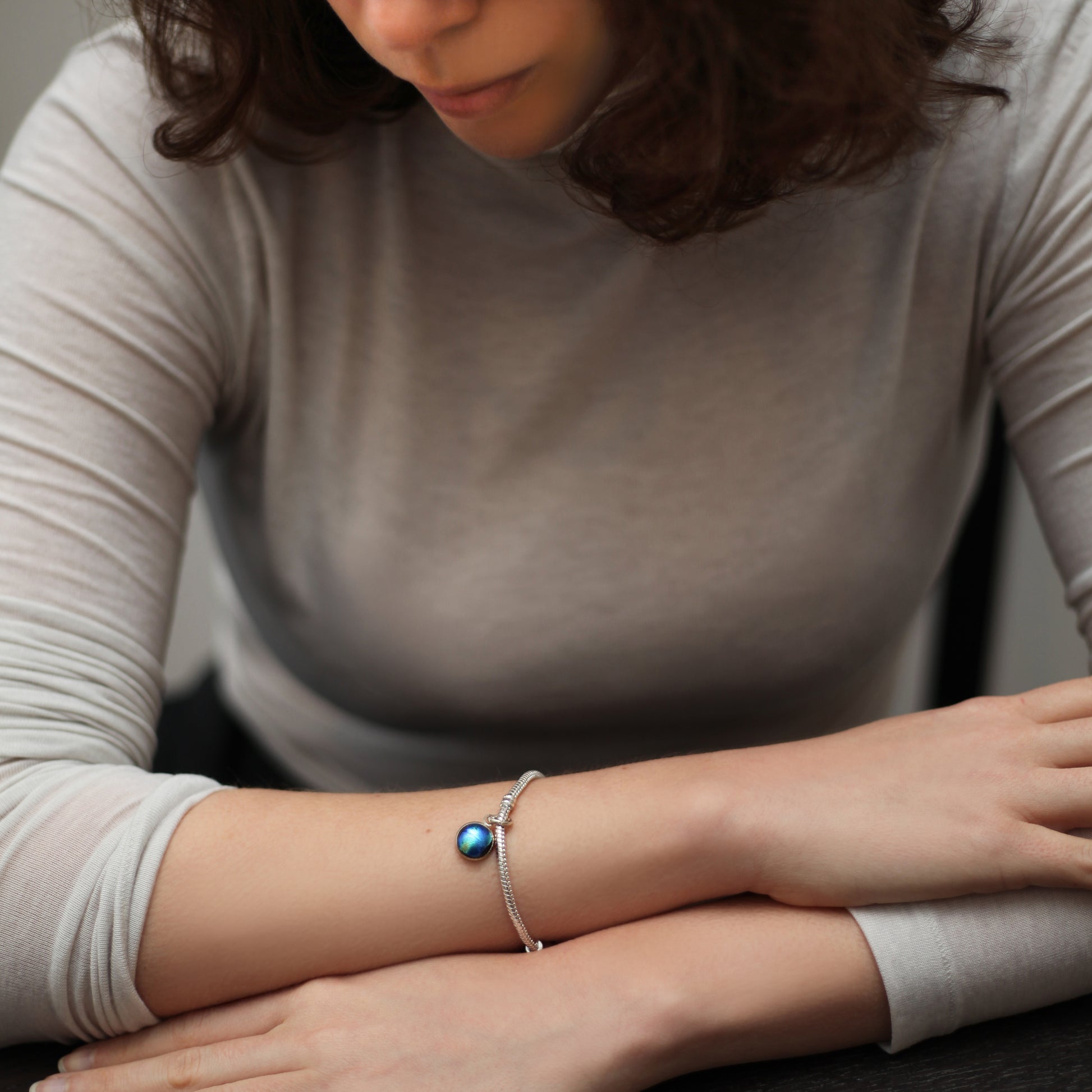Woman wearing a bracelet with a blue gemstone on her wrist.