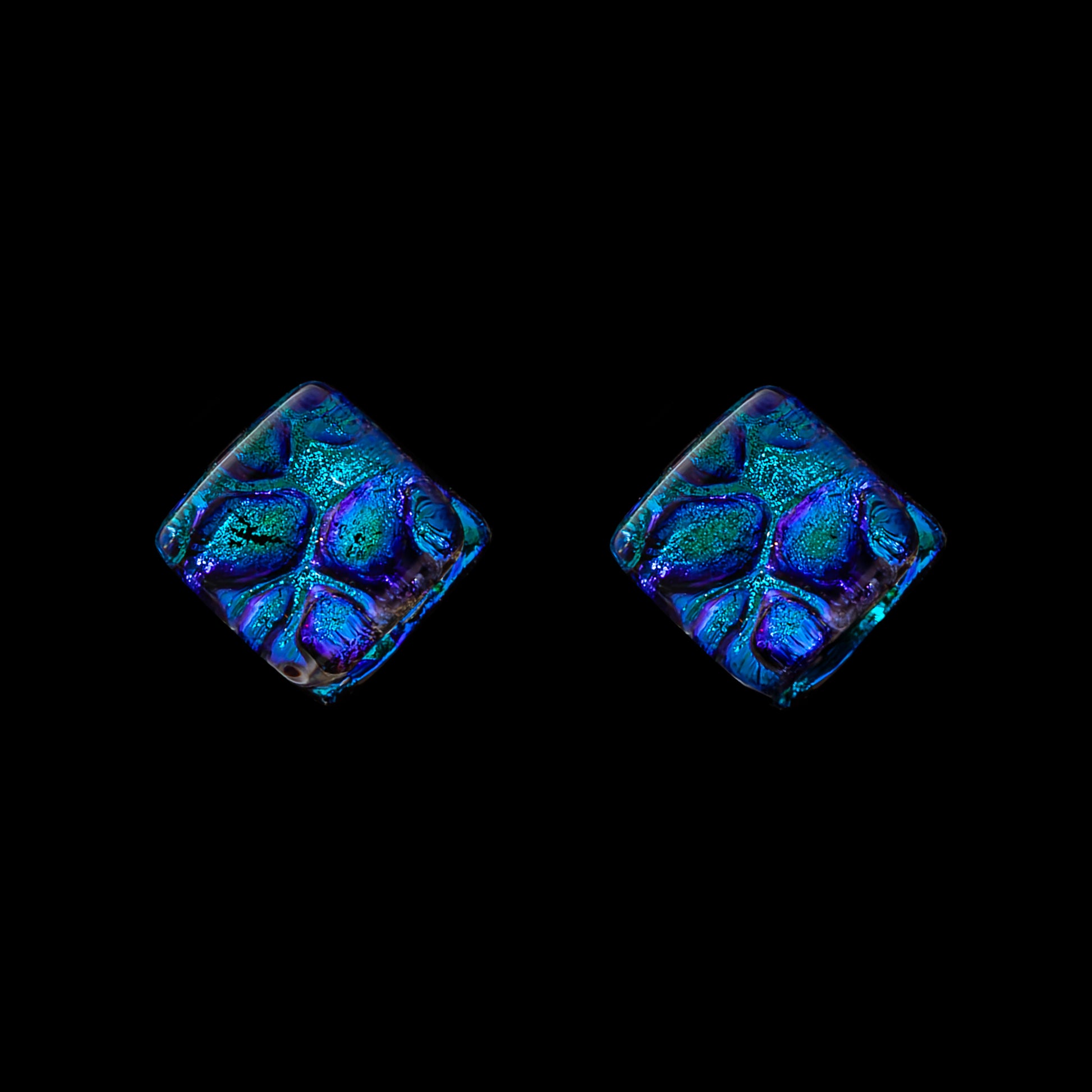 A pair of blue cube-shaped stud earrings with a geometric pattern, set against a black background.