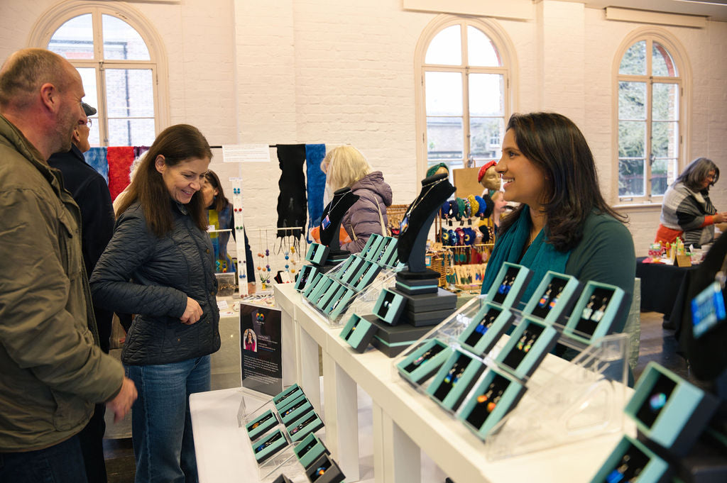 Madiha Zaidi chatting with customers at her Invoke London handmade dichroic glass jewellery stall at Orleans House Gallery Christmas Fair.